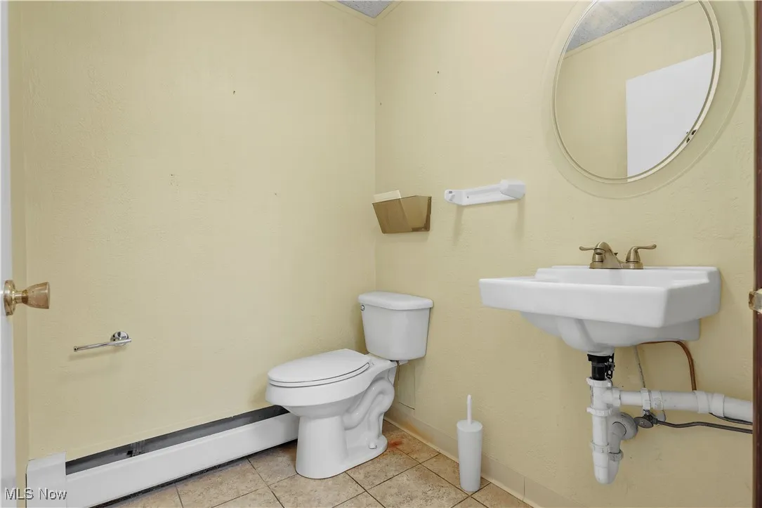 Half bathroom featuring baseboard heating and tile patterned floors