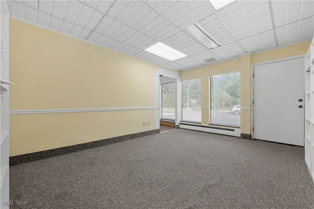 Empty room with baseboard heating and carpet