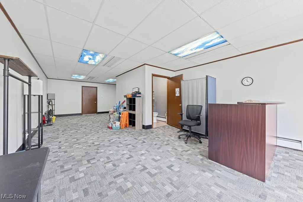 Office area featuring carpet, a drop ceiling, and a baseboard radiator