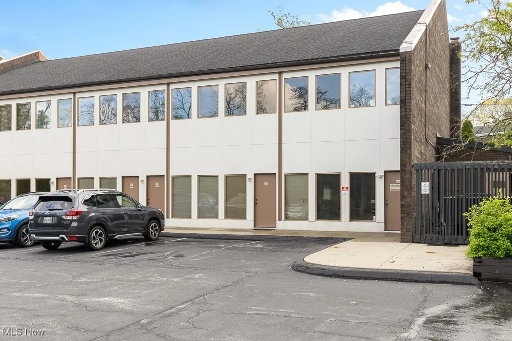 View of building exterior featuring uncovered parking and fence
