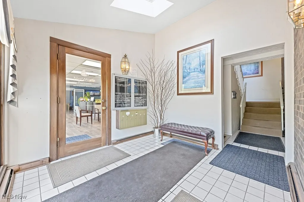 Doorway to outside featuring a skylight, tile patterned flooring, stairs, and a baseboard radiator
