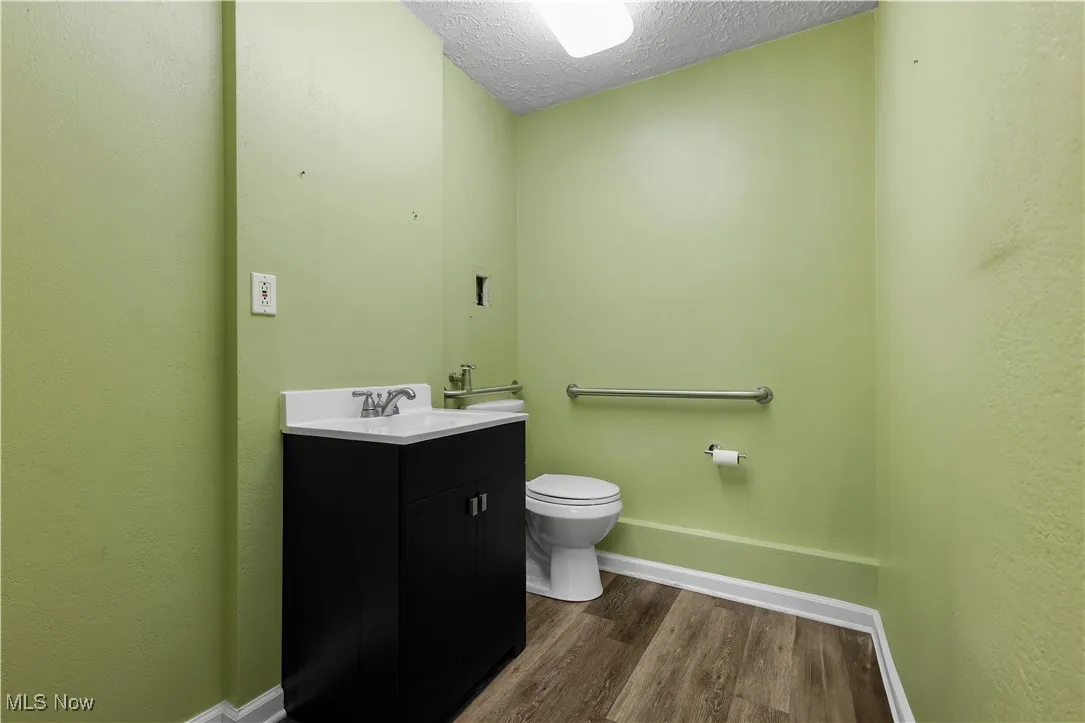 Bathroom with wood finished floors, vanity, and a textured ceiling