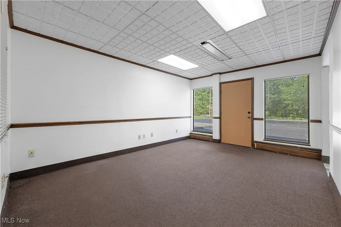 Carpeted empty room featuring crown molding and baseboards