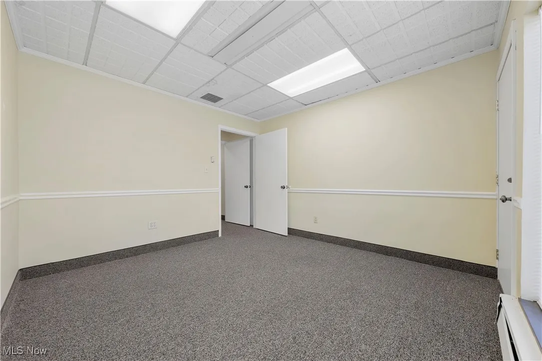 Spare room with baseboard heating, carpet, and a paneled ceiling
