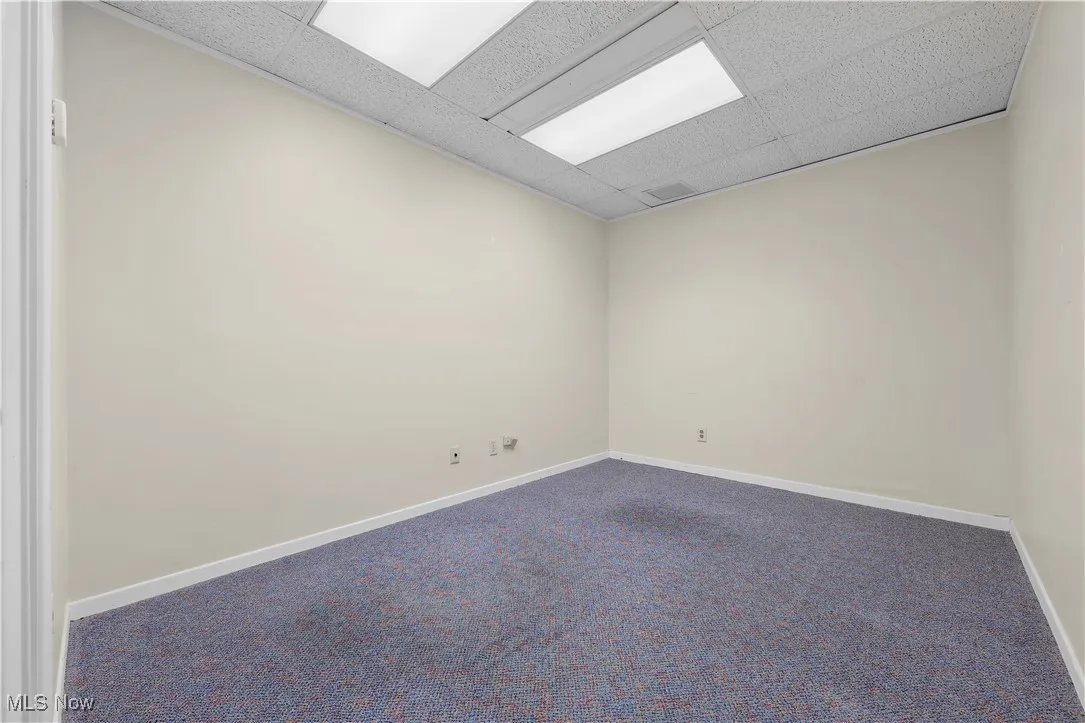 Carpeted spare room featuring a drop ceiling