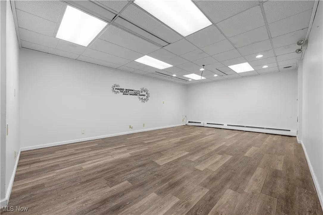 Unfurnished room with baseboard heating, wood finished floors, a paneled ceiling, and recessed lighting
