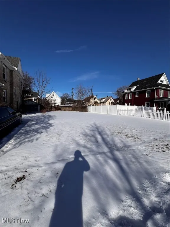 Snowy yard featuring fence and a residential view