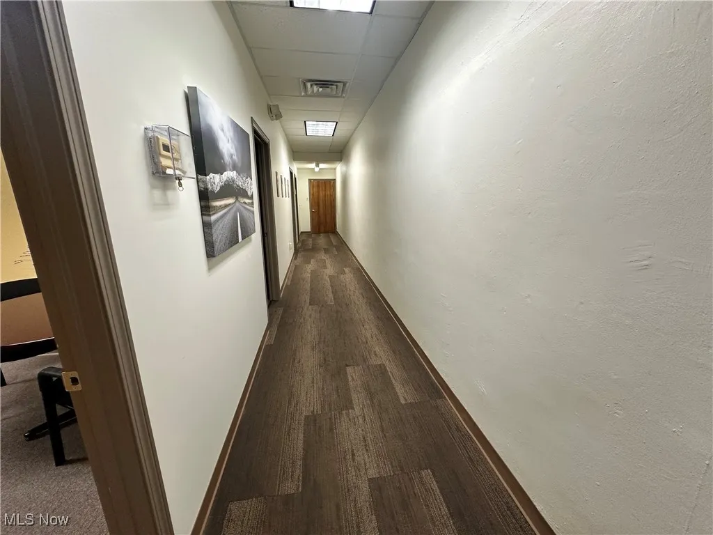 Hall featuring dark wood-type flooring and a paneled ceiling