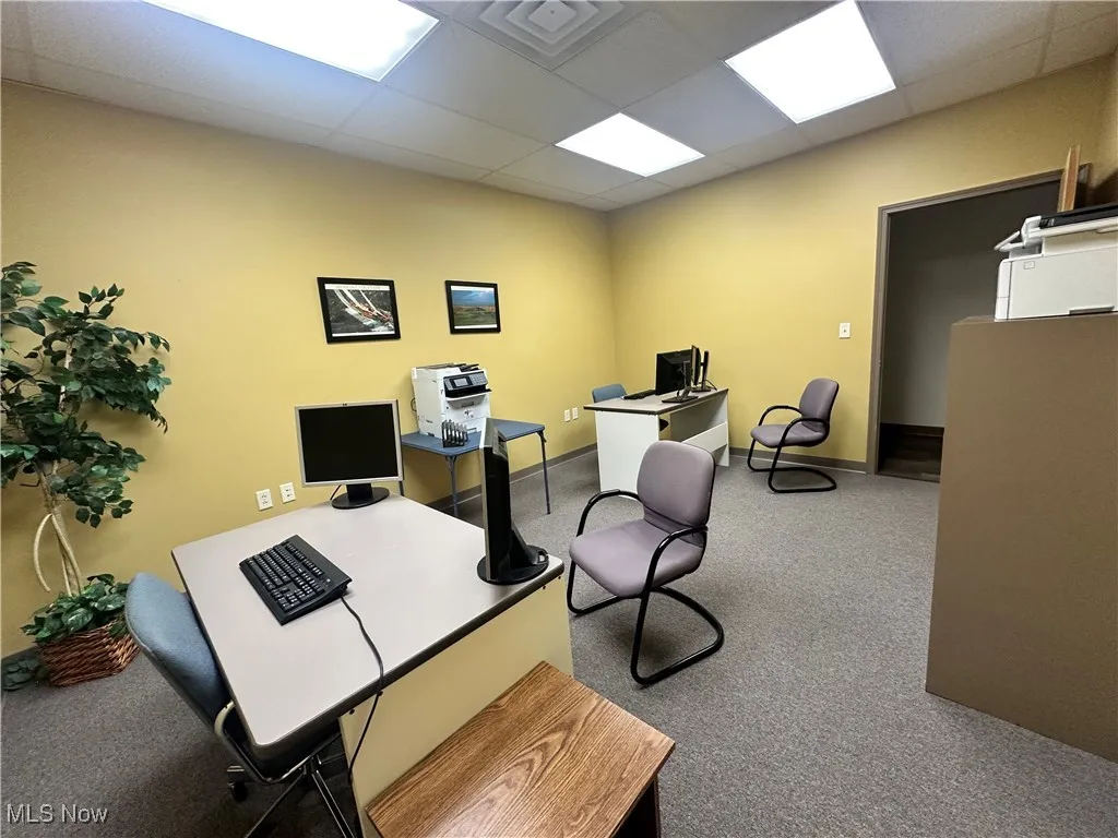 Carpeted office featuring a drop ceiling and baseboards