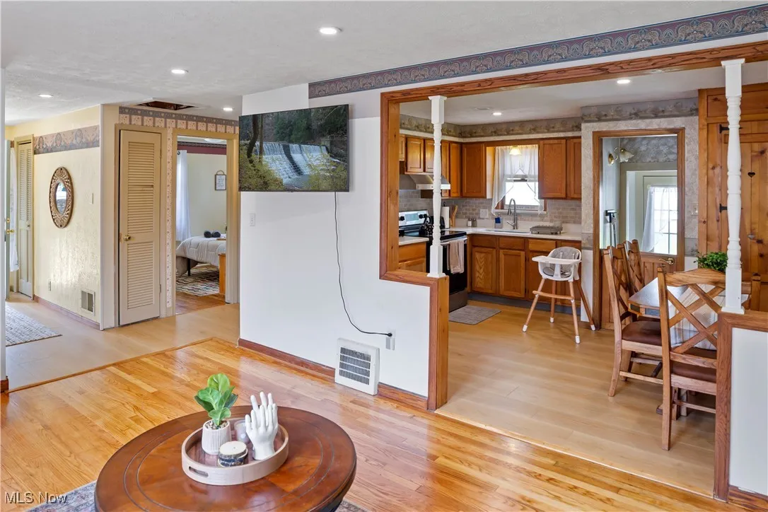 Living room featuring visible vents, decorative columns, light wood-style flooring, and recessed lighting