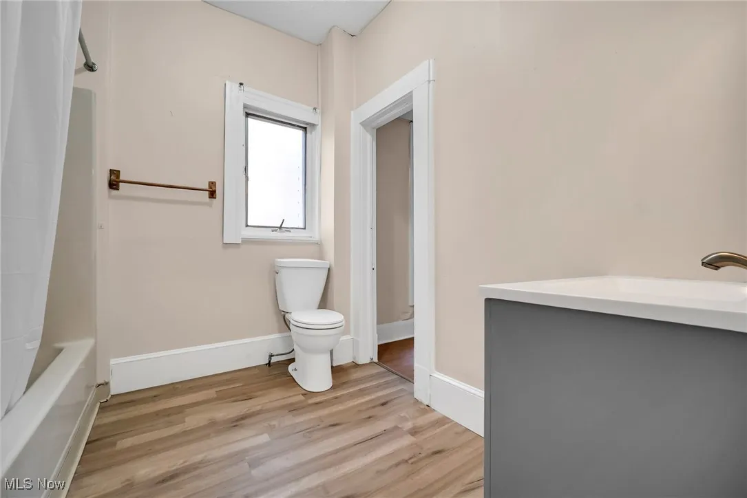 Full bath with shower / bath combination with curtain, baseboards, toilet, and wood finished floors