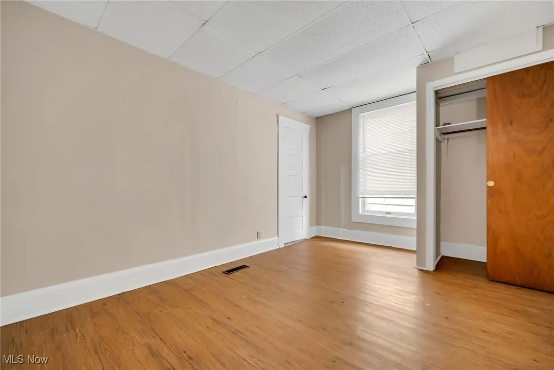 Unfurnished bedroom with visible vents, light wood-style flooring, and baseboards