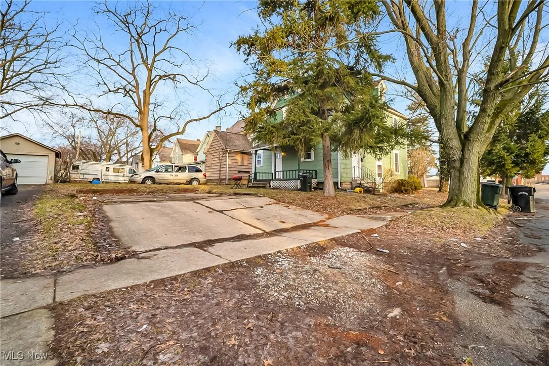 View of front of house featuring a garage, a porch, concrete driveway, and an outbuilding