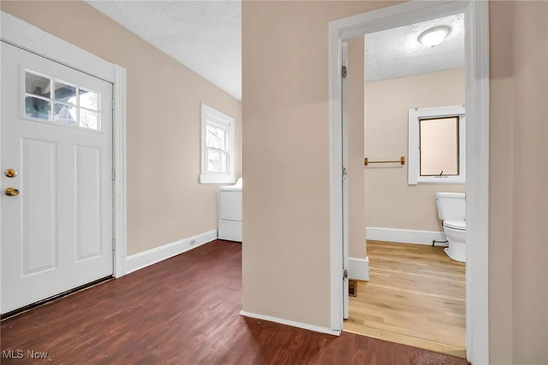 Foyer with baseboards, a textured ceiling, and wood finished floors