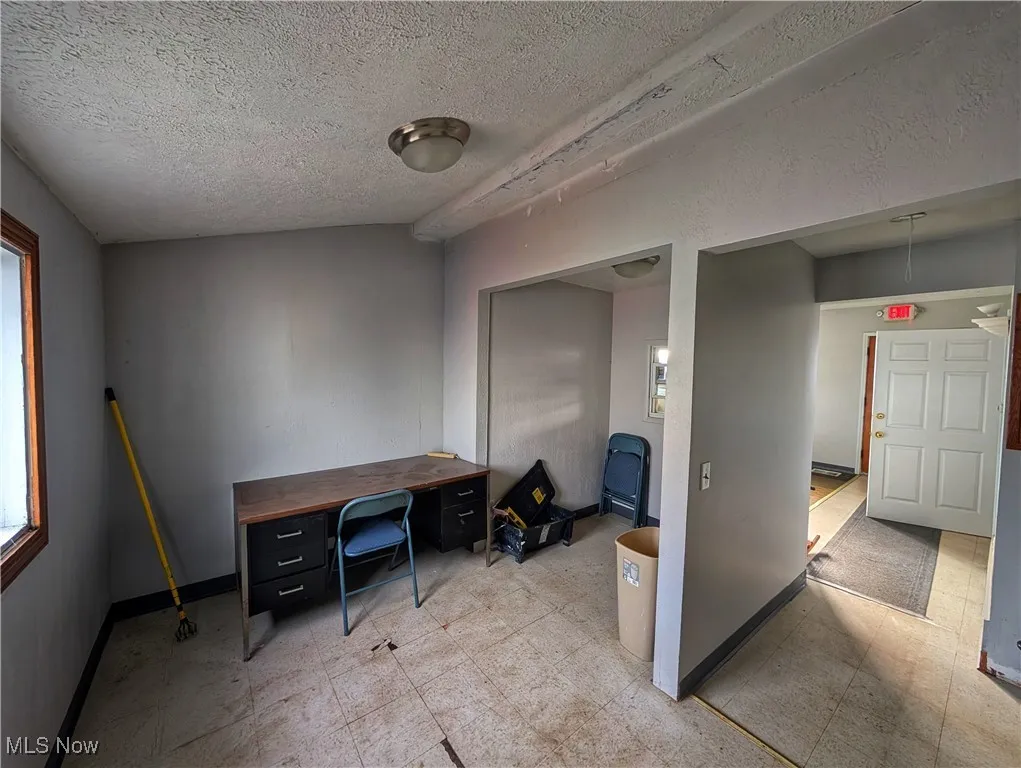 Office with a textured ceiling, light floors, and baseboards
