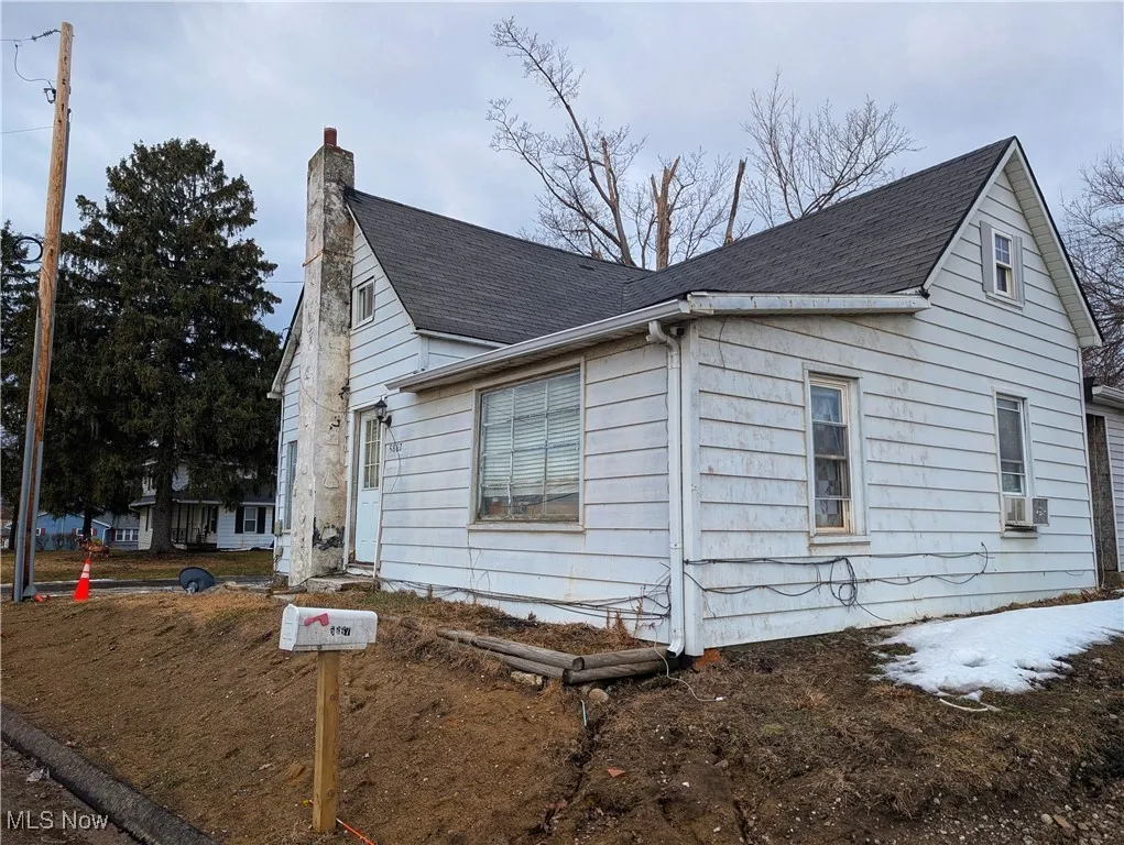 View of side of property featuring a shingled roof, cooling unit, and a chimney