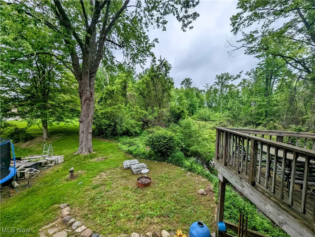 View of green lawn featuring a trampoline and a fire pit