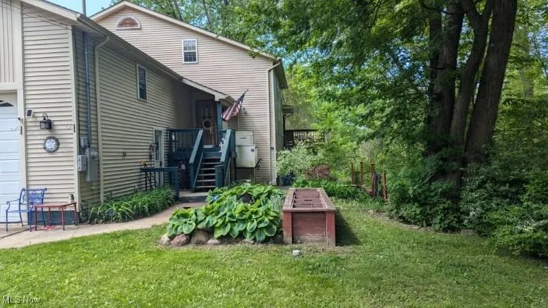 Rear view of property with a lawn, a garage, and stairway