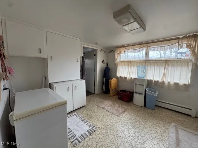 Kitchen featuring fridge, a baseboard radiator, white cabinetry, and light countertops