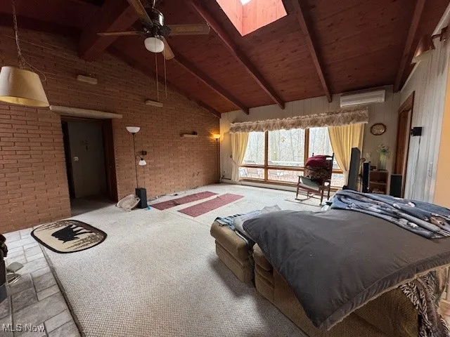 Bedroom featuring a skylight, wood ceiling, brick wall, beamed ceiling, and a wall mounted air conditioner