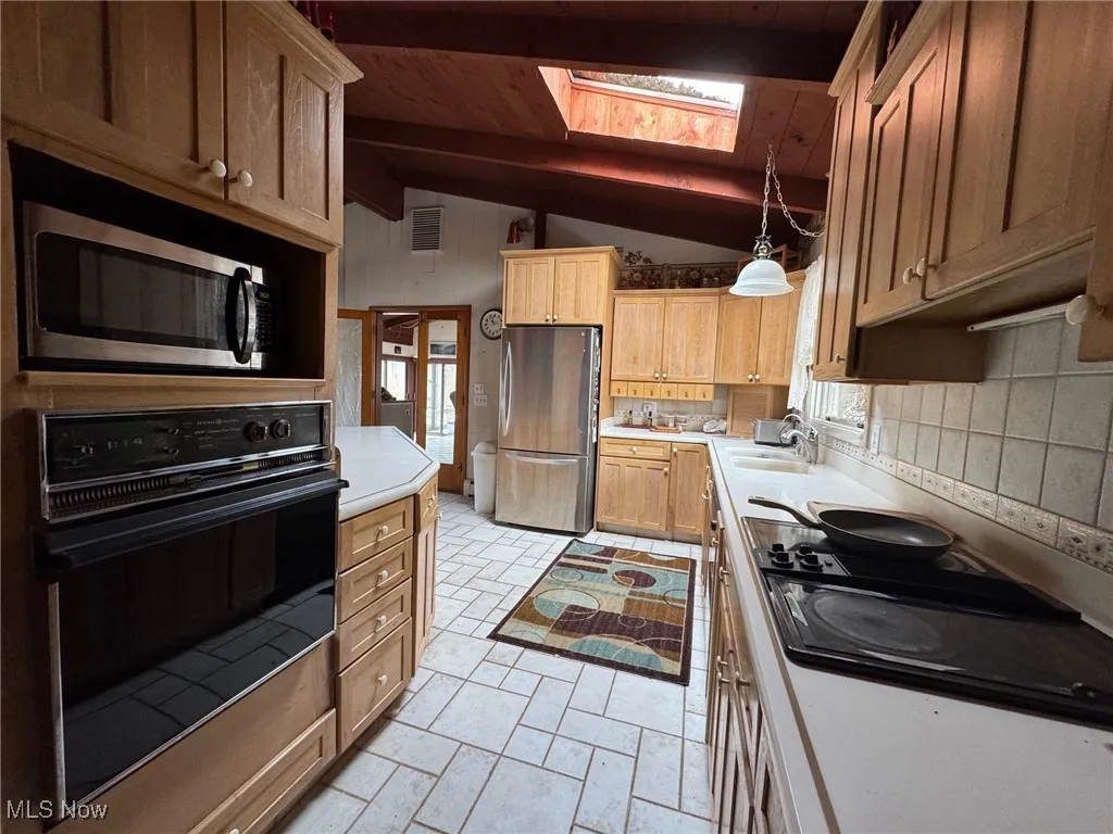 Kitchen featuring a sink, visible vents, light countertops, black appliances, and pendant lighting