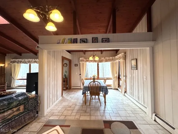 Dining area with wooden ceiling, a baseboard heating unit, and stone tile flooring