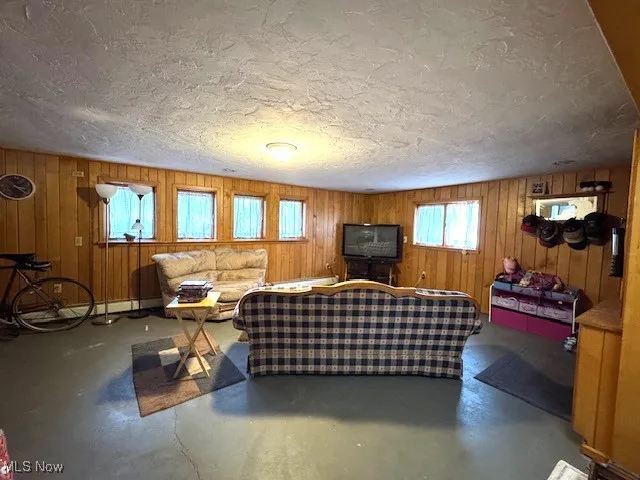 Living area featuring a baseboard heating unit, concrete floors, and a textured ceiling