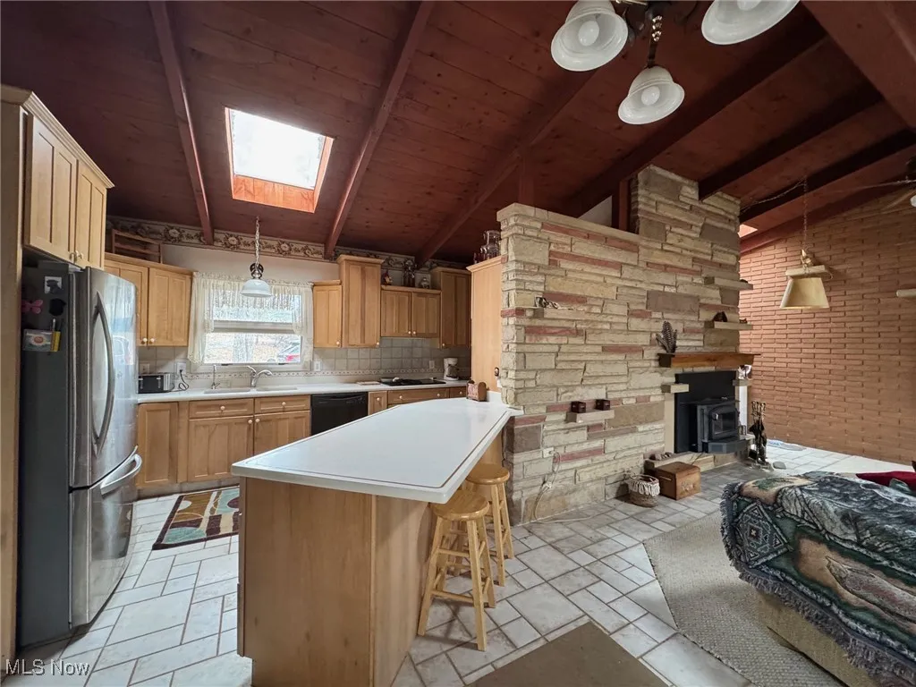 Kitchen with a kitchen island, light countertops, freestanding refrigerator, dishwasher, and pendant lighting