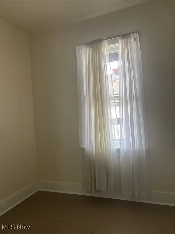 Spare room with dark wood-style flooring and baseboards