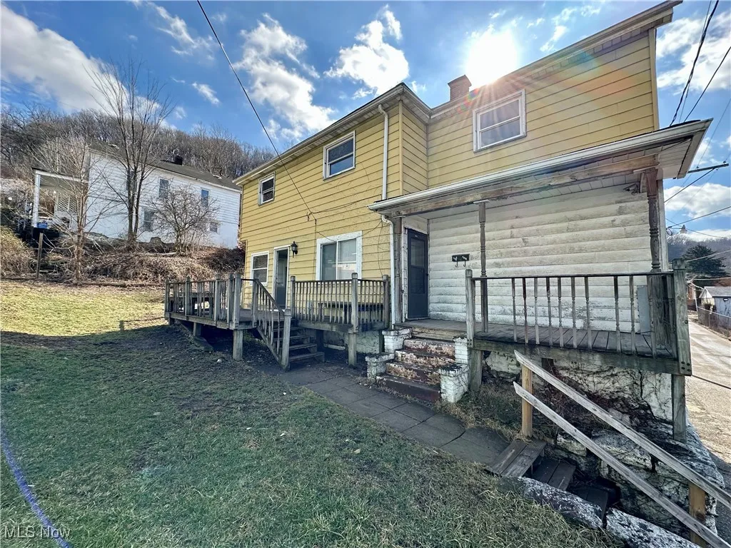 front of home with a lawn and a wooden deck