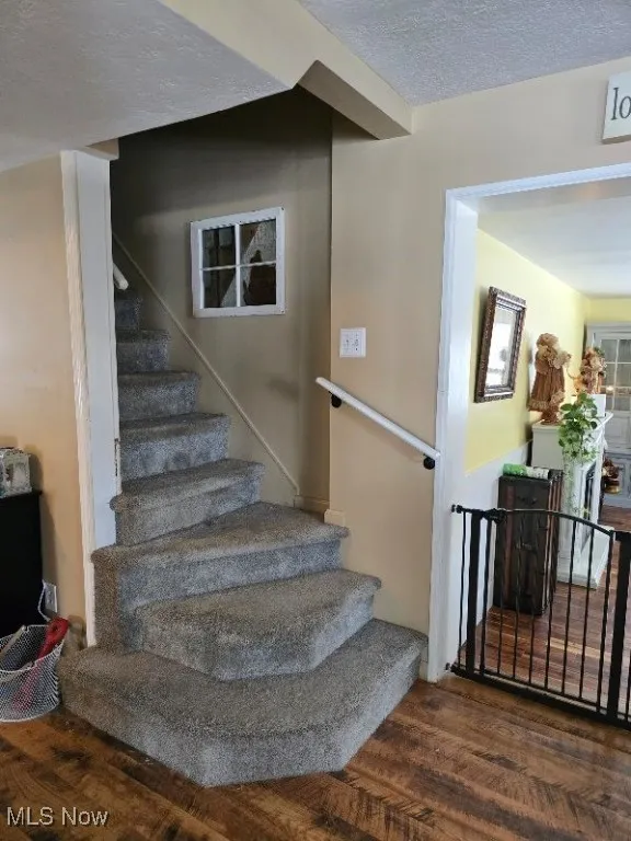 Staircase featuring a textured ceiling and wood finished floors