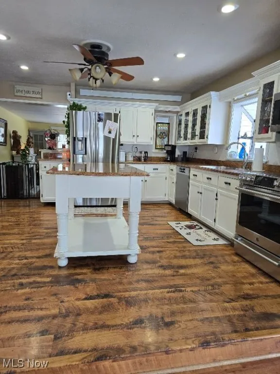 Kitchen with appliances with stainless steel finishes, dark wood-style flooring, and white cabinets