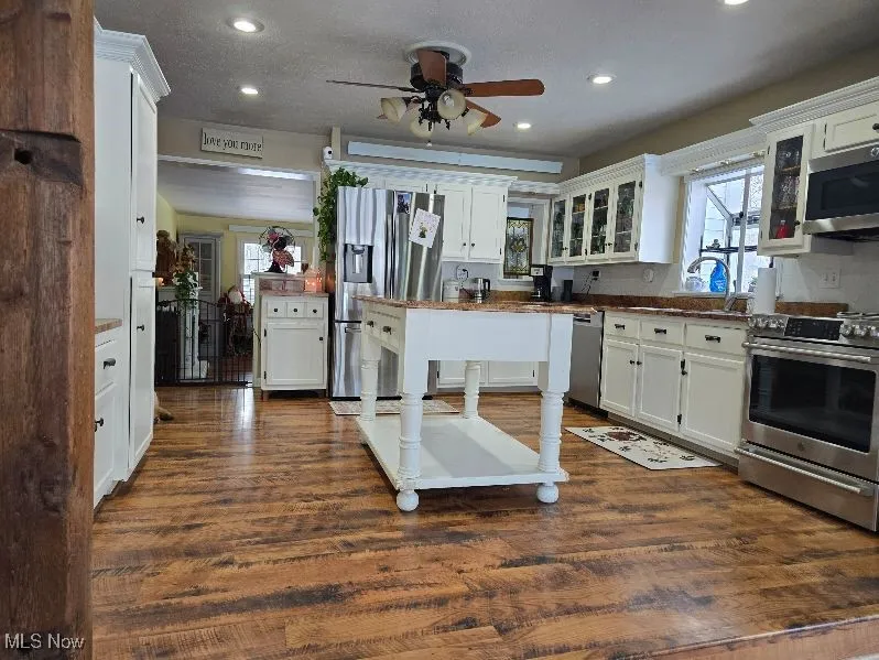 Kitchen featuring appliances with stainless steel finishes, dark wood-style flooring, white cabinetry, and glass insert cabinets