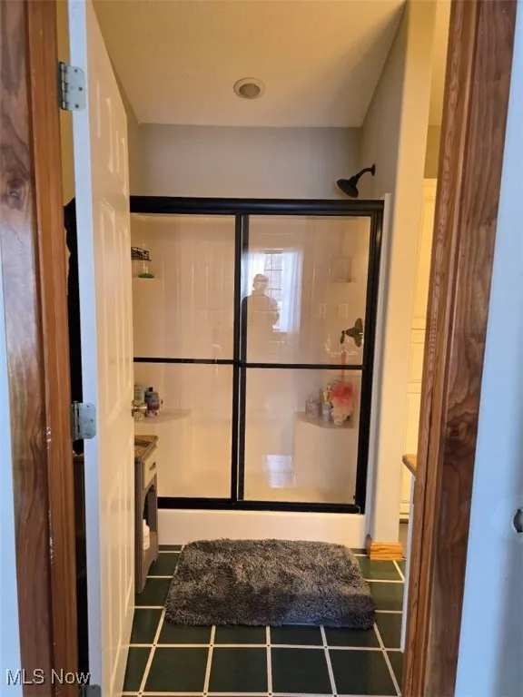 Bathroom with a stall shower and tile patterned flooring