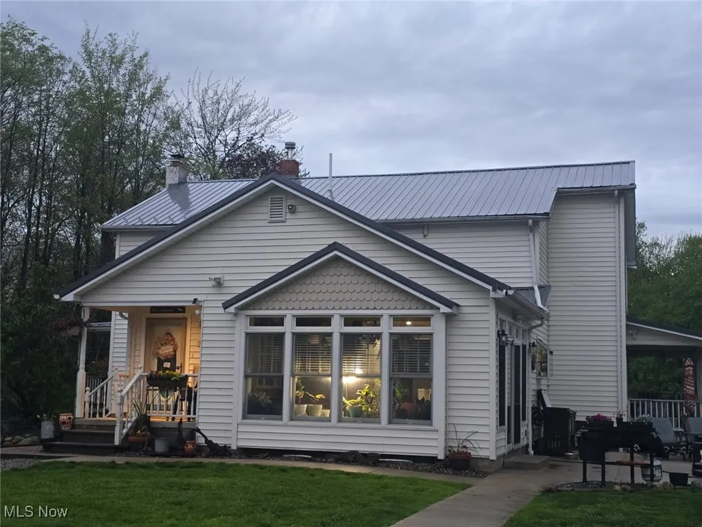 Back of property featuring a lawn, a chimney, and metal roof