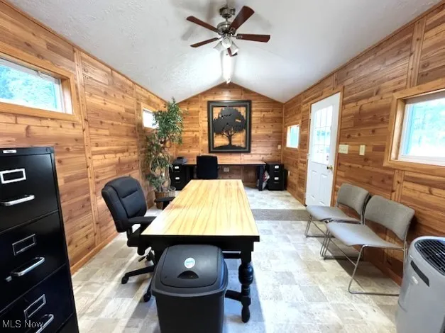 Office with a ceiling fan, vaulted ceiling, and knotty pine walls