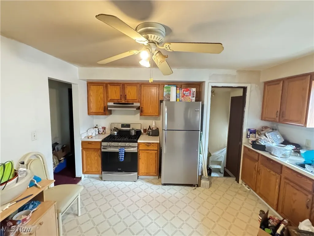 Kitchen with stainless steel appliances, brown cabinets, light countertops, and light flooring