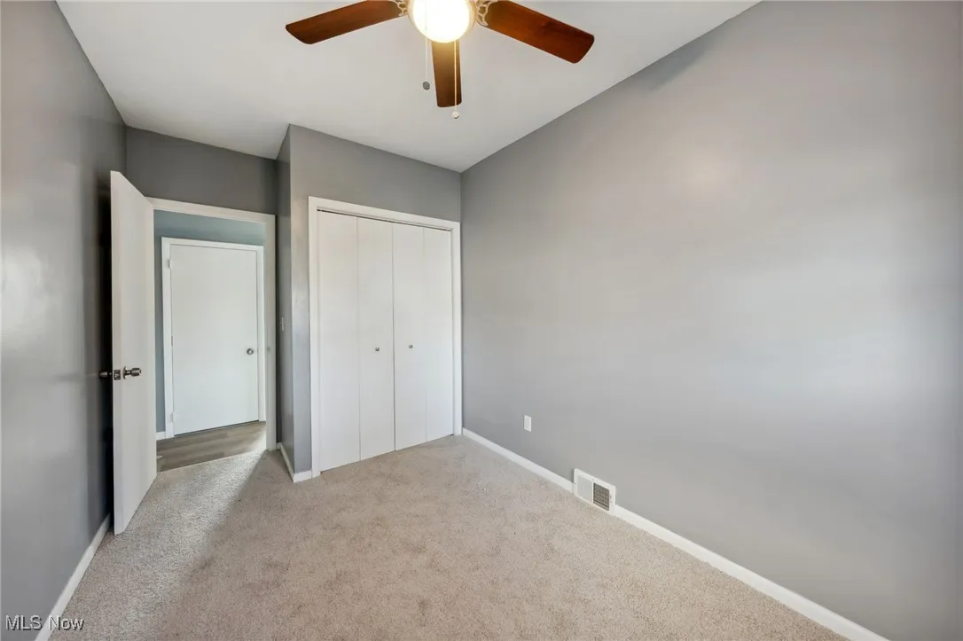 Unfurnished bedroom with carpet floors, a ceiling fan, visible vents, baseboards, and a closet