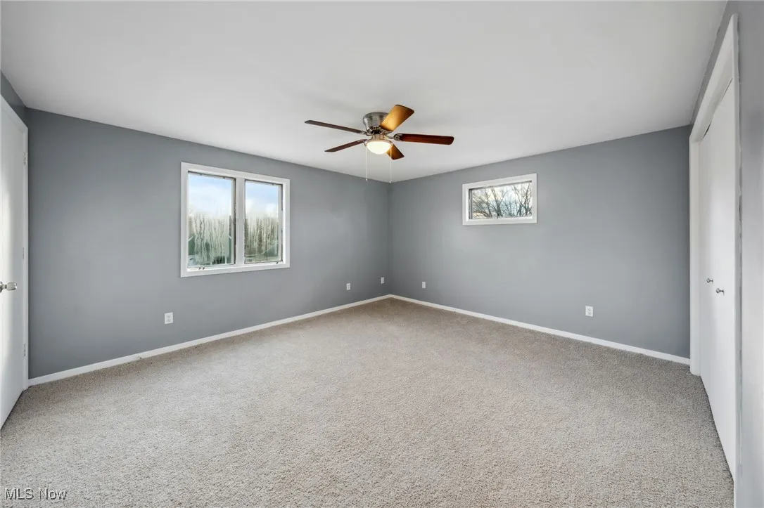 Empty room with carpet floors, baseboards, and a ceiling fan