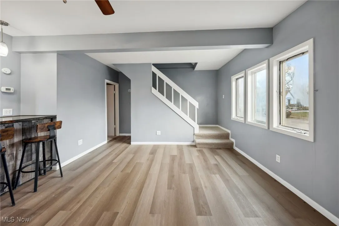 Living room with wood finished floors, baseboards, a bar, and stairs