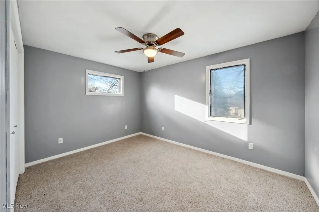 Spare room featuring carpet, a ceiling fan, and baseboards