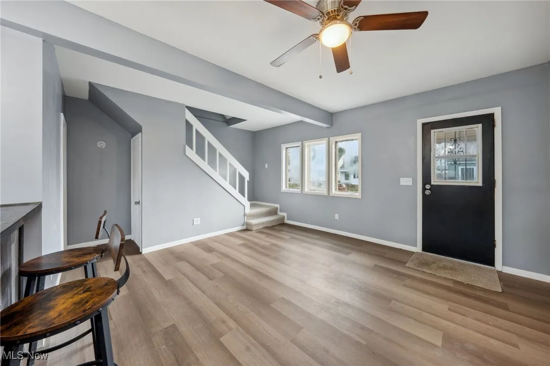 Foyer with stairs, wood finished floors, beam ceiling, and baseboards