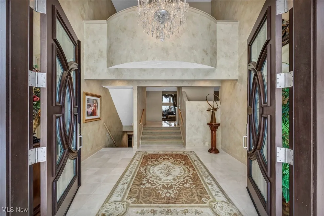 Elegant 8' double door Entrance into 3 story foyer, elevator door at top of stairway on the right.