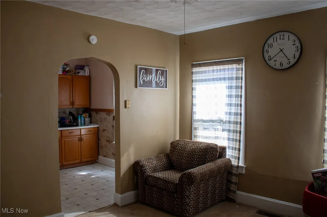 Living area with arched walkways, baseboards, visible vents, and light floors