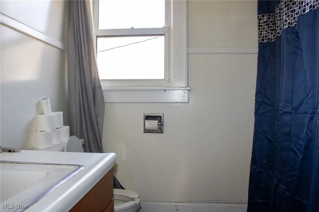 Full bath featuring curtained shower, vanity, and toilet