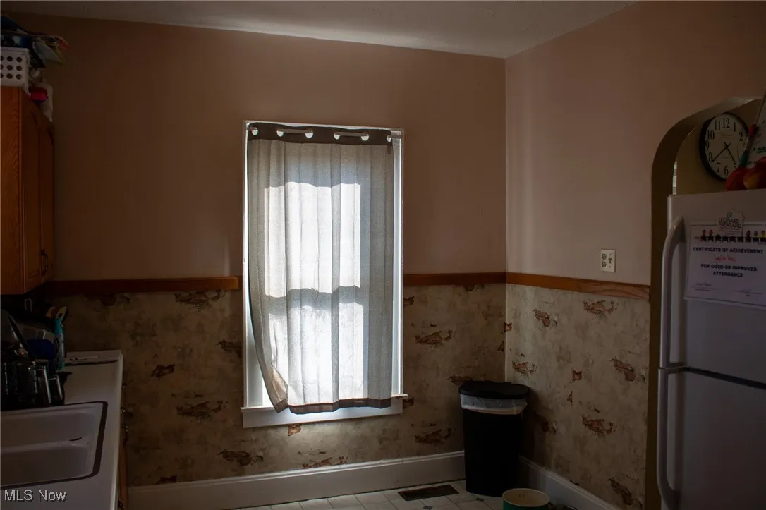 Kitchen with freestanding refrigerator, wainscoting, a sink, and visible vents
