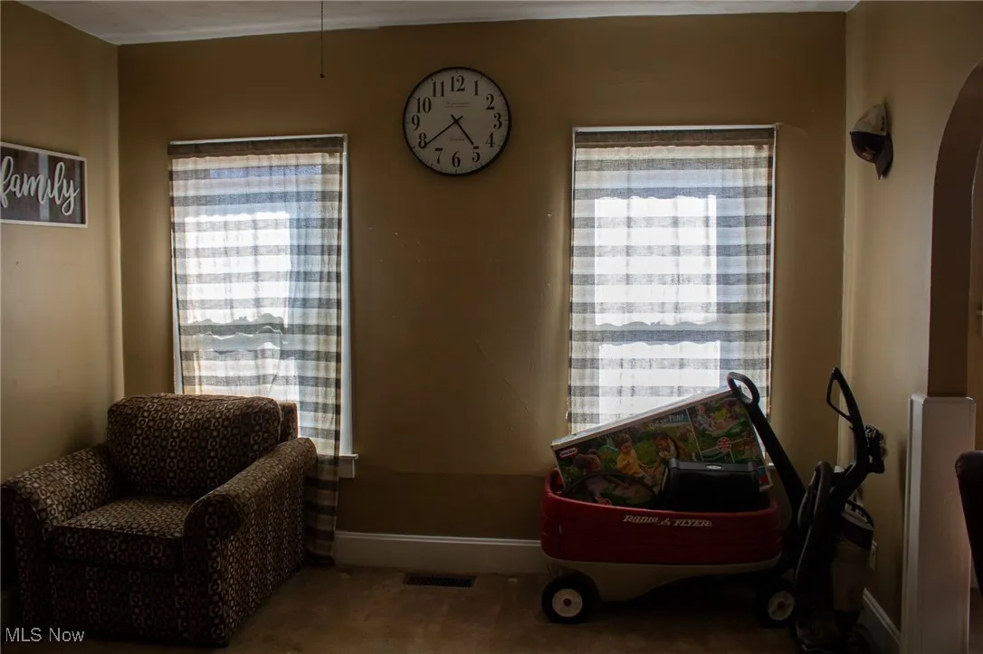 Living area with arched walkways, baseboards, and carpet