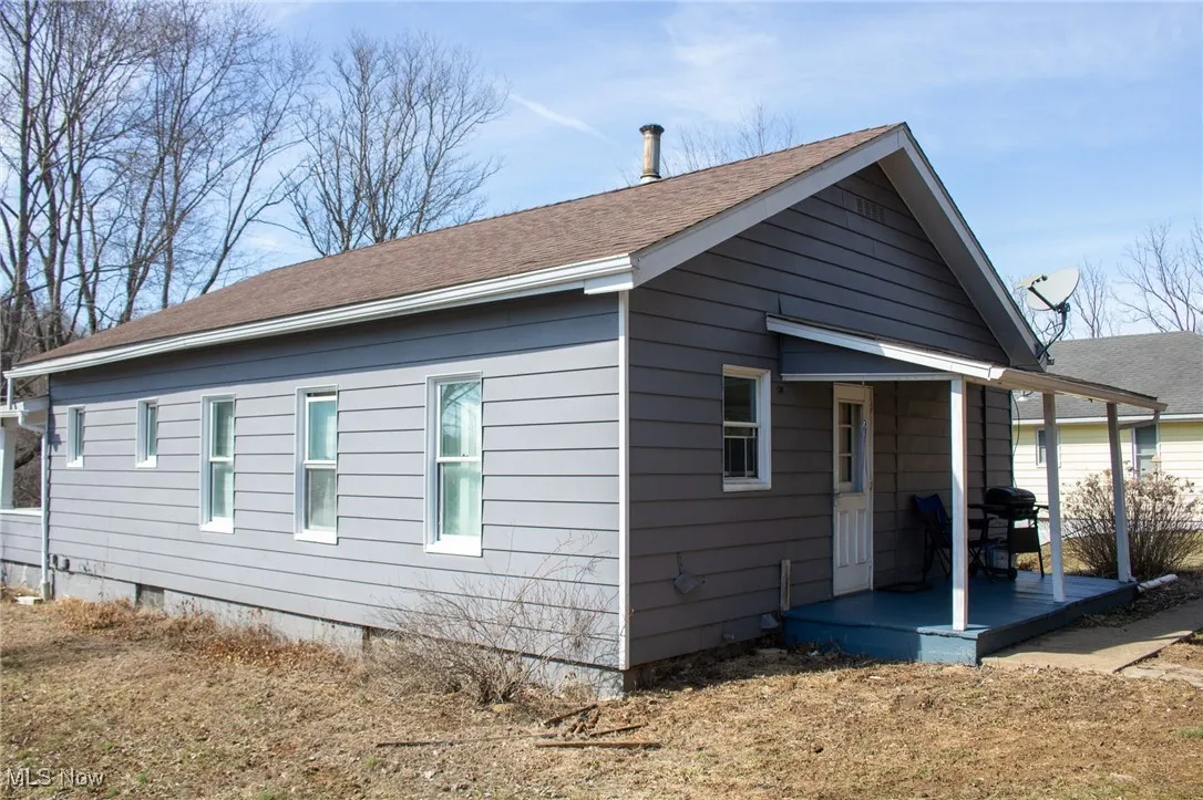 View of back of home featuring roof with shingles and crawl space