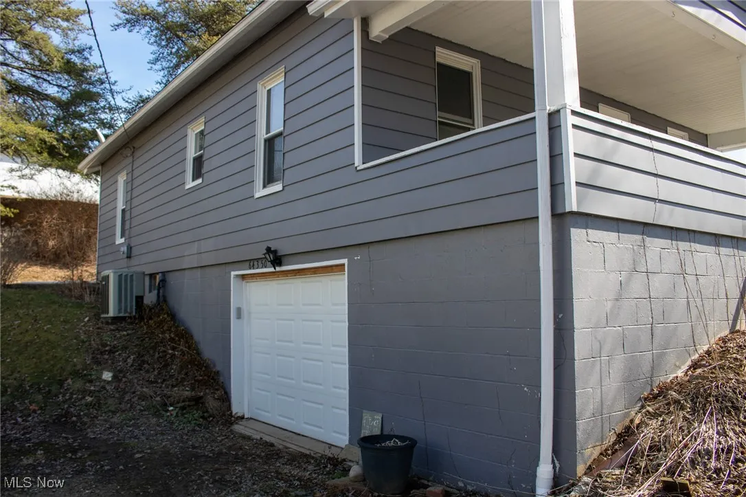 View of side of property featuring an attached garage and central air condition unit