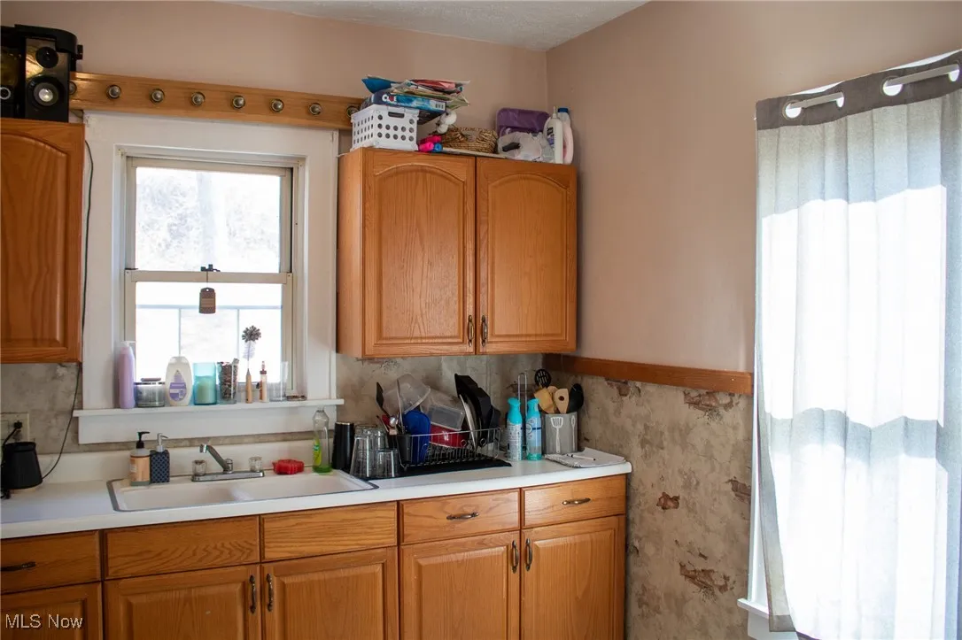 Kitchen with light countertops, brown cabinetry, and a sink